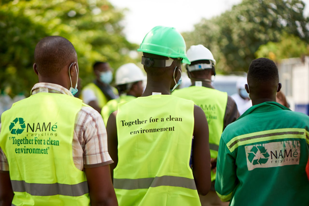 Home Group of workers wearing reflective vests and helmets on a recycling project day. Focus on sustainability.