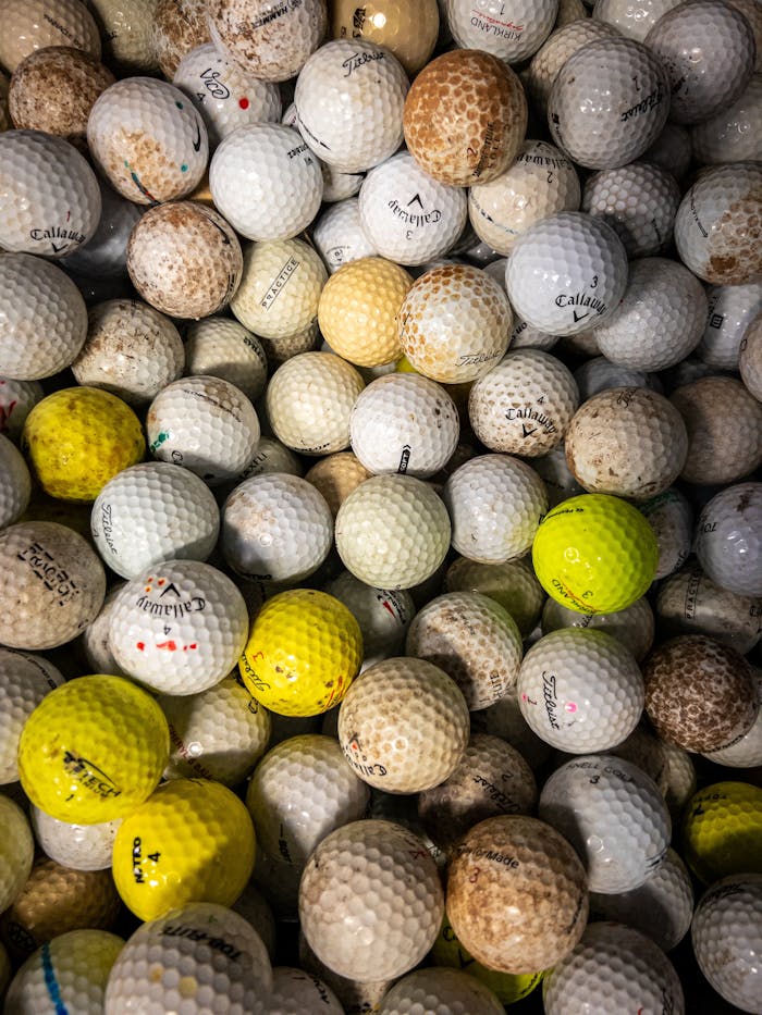 A top view of assorted used golf balls in various colors and conditions.
