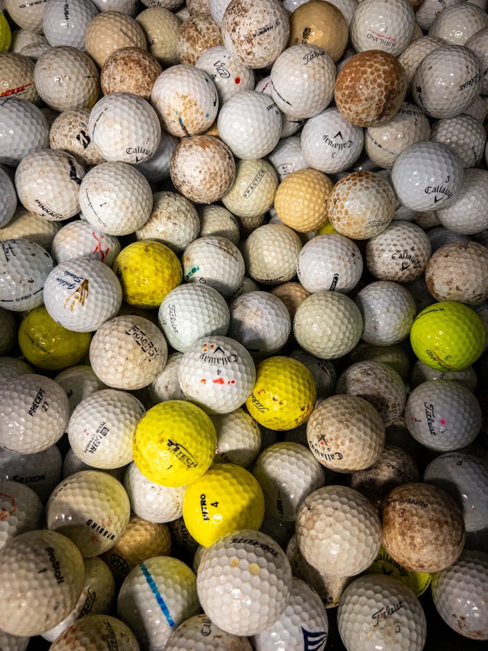 Close-up of a pile of used golf balls showcasing various brands and colors.